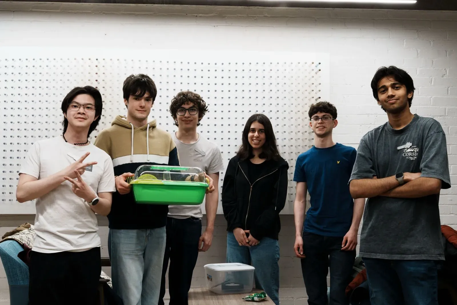 The hackathon team holding up the hamster enclosure